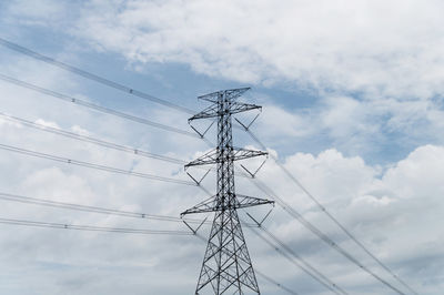 Low angle view of electricity pylon against cloudy sky