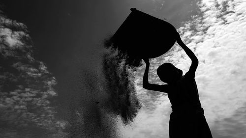 Silhouette woman holding basket against sky