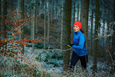 Boy holding umbrella in forest during winter