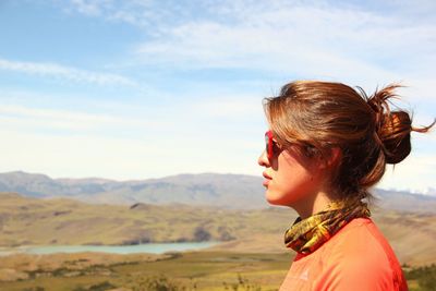 Young woman looking at mountains against sky