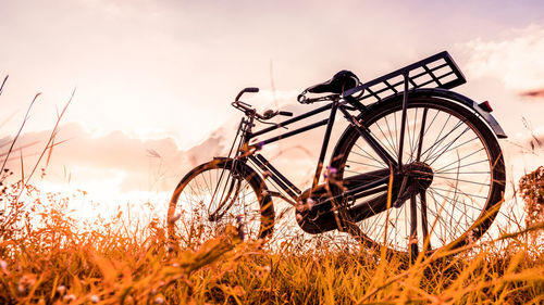 Bicycle on field against sky during sunset