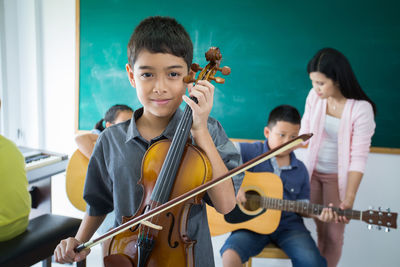 Portrait of boy playing violin in classroom