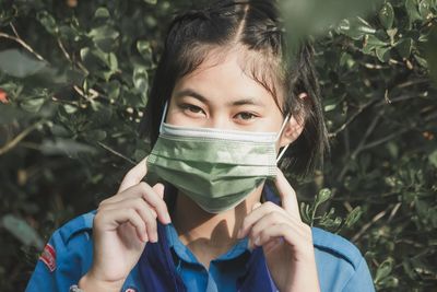 Portrait of young woman wearing face mask the item amid coronavirus pandemic