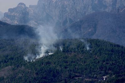 Aerial view of small village and hill on fire and smoke. a helicopter extinguish a fire 