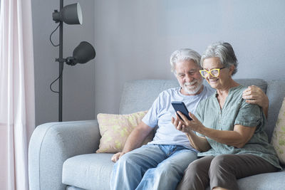 Friends using mobile phone while sitting on sofa