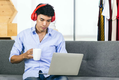 Mid adult man using mobile phone sitting at home