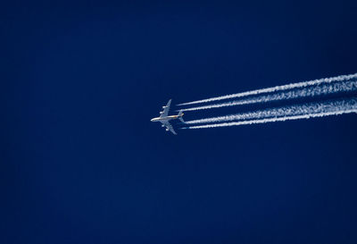 Low angle view of airplane flying against clear blue sky
