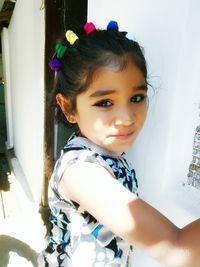 Portrait of cute girl standing against wall