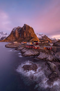 Scenic view of sea by mountain against sky during sunset