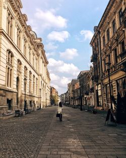 Rear view of woman walking on street amidst buildings