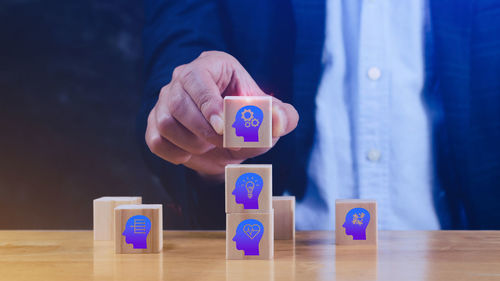 Midsection of man holding toy blocks on table