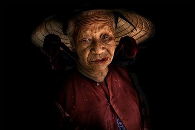 Portrait of man wearing hat against black background