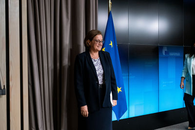 Young woman looking away while standing against blue wall