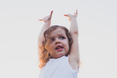 Portrait of girl with arms raised against white background