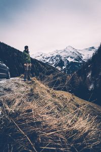 Man standing on snowcapped mountain against sky