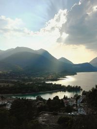 Scenic view of river by mountains against sky