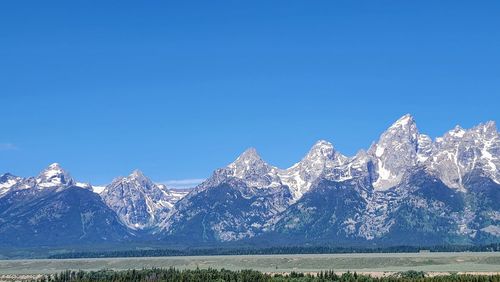 Scenic view of snowcapped mountains against clear blue sky