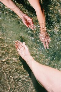 Cropped hands touching sea water