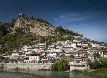 Buildings by river against sky in town