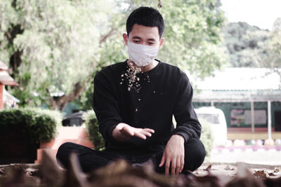 Young man catching stones while sitting on field