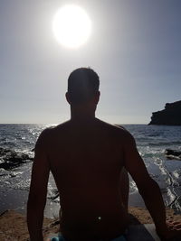 Rear view of man on beach against sky