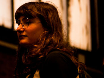 Side view of woman wearing eyeglasses while looking away at night