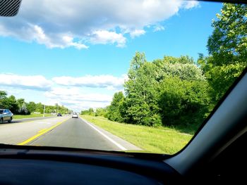 Road amidst trees seen through car windshield