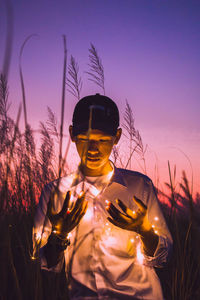 Man standing by sculpture against sky during sunset