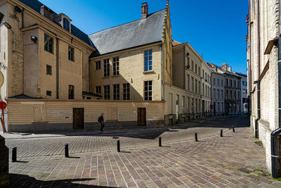 Footpath by buildings against blue sky