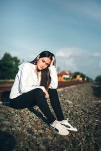 Portrait of smiling young woman sitting on land