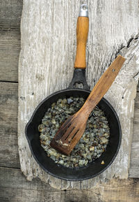 Directly above shot of fried onion in skillet at wooden table