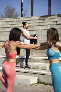 Male and female friends doing stretching exercise