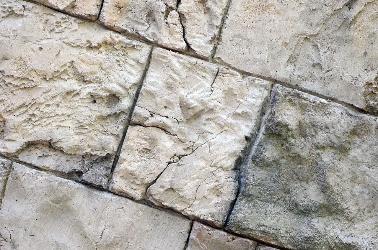 HIGH ANGLE VIEW OF STONE WALL WITH SHADOW ON TILED FLOOR