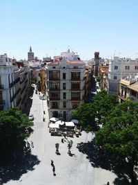 Buildings by road against clear sky in city