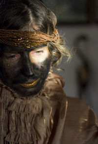 A woman with black painted face and golden clothes, party time, festival, close up portrait