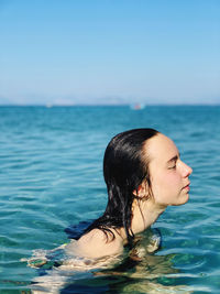 Woman swimming in pool against sea