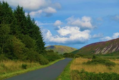 Empty road amidst landscape against sky