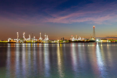 Illuminated city at waterfront during sunset