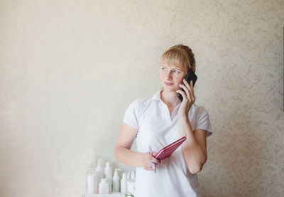 Side view of young woman looking away while standing against wall