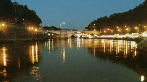 Illuminated bridge over river against sky at night