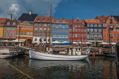 Sailboats moored on canal by buildings in city against sky