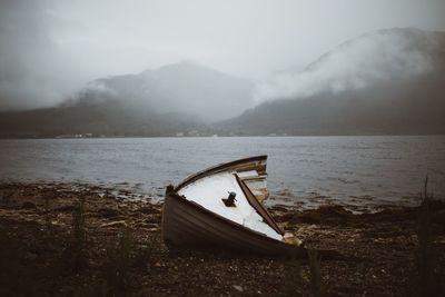 Abandoned boat moored on lake against sky