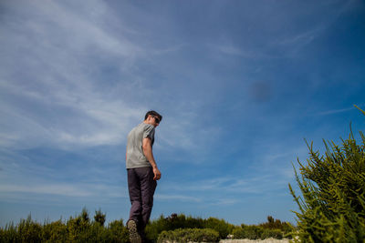 Low angle view of man standing on field against sky