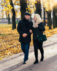 Full length of friends standing in park during autumn