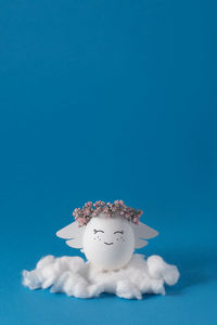 Smiling angel in wreath of pink gypsophila flowers with white cloud. easter egg. 