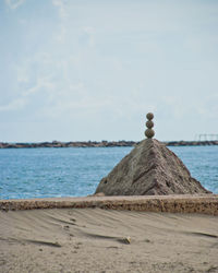 Stacked pebble on rock against sea