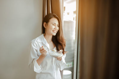 Happy young woman drinking from glass window