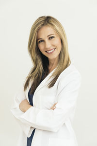 Portrait of female doctor smiling while standing against white background