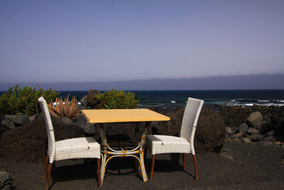 Chairs on beach against clear sky