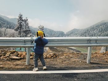 Rear view of man standing on mountain against sky